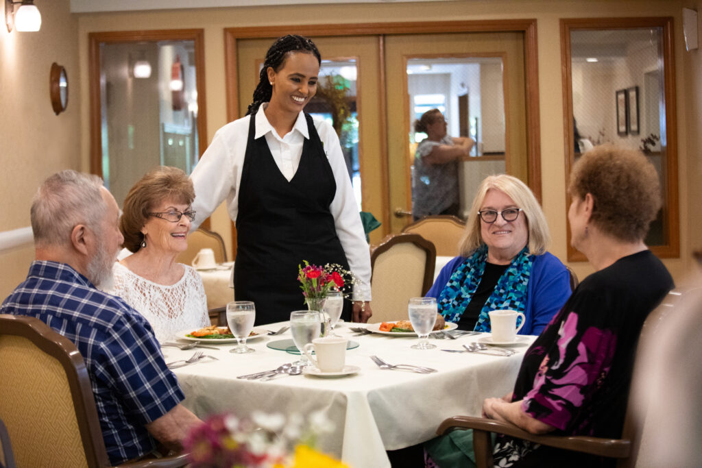 Smiling residents enjoying a meal in Assisted Living