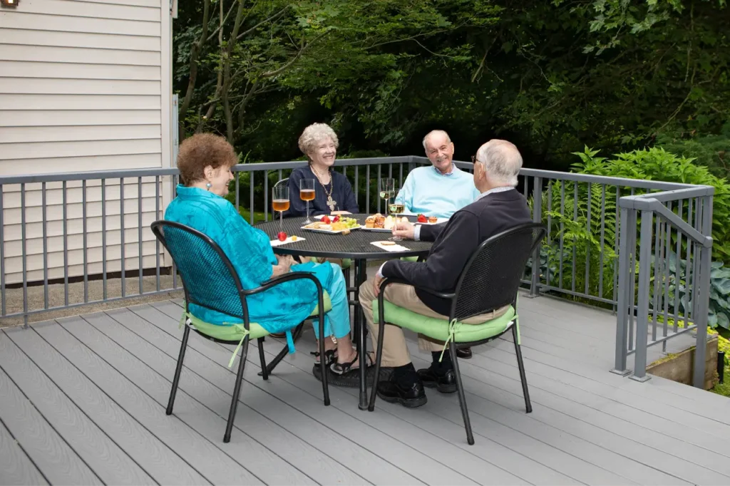 Four seniors enjoying friendships in community living on a modern deck.