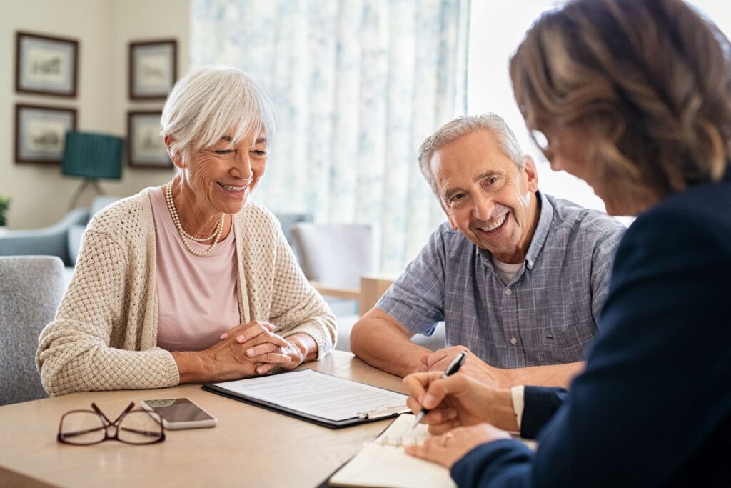 Smiling older couple meeting with a professional to discuss Powers of Attorney for Seniors.