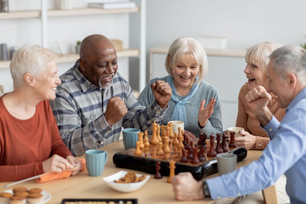 Older adults enjoying chess, coffee, and conversation together, highlighting assisted living daily life benefits.