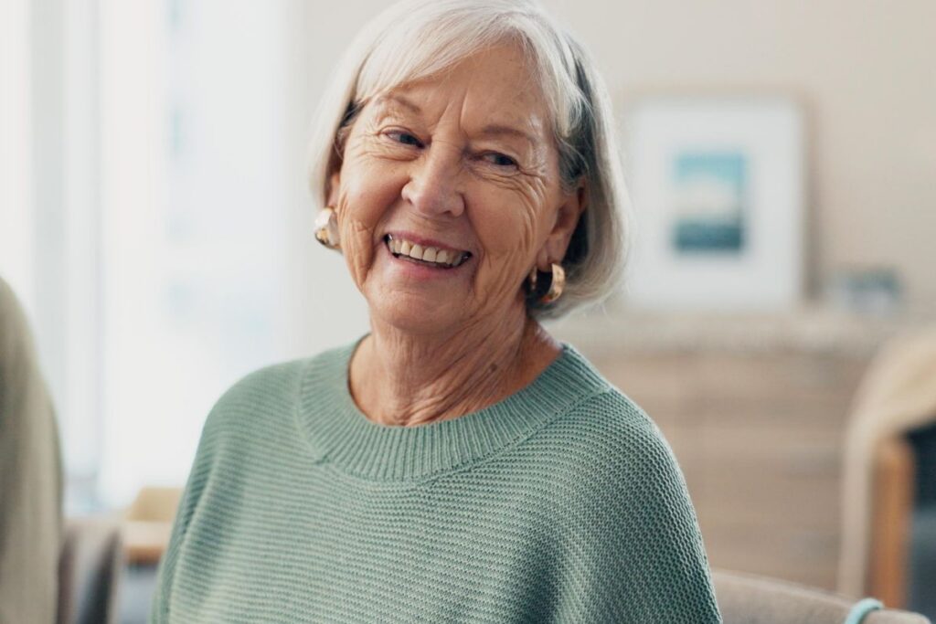 Happy senior woman smiling confidently in a warm community setting, reflecting independence with support at Village Green Senior Living